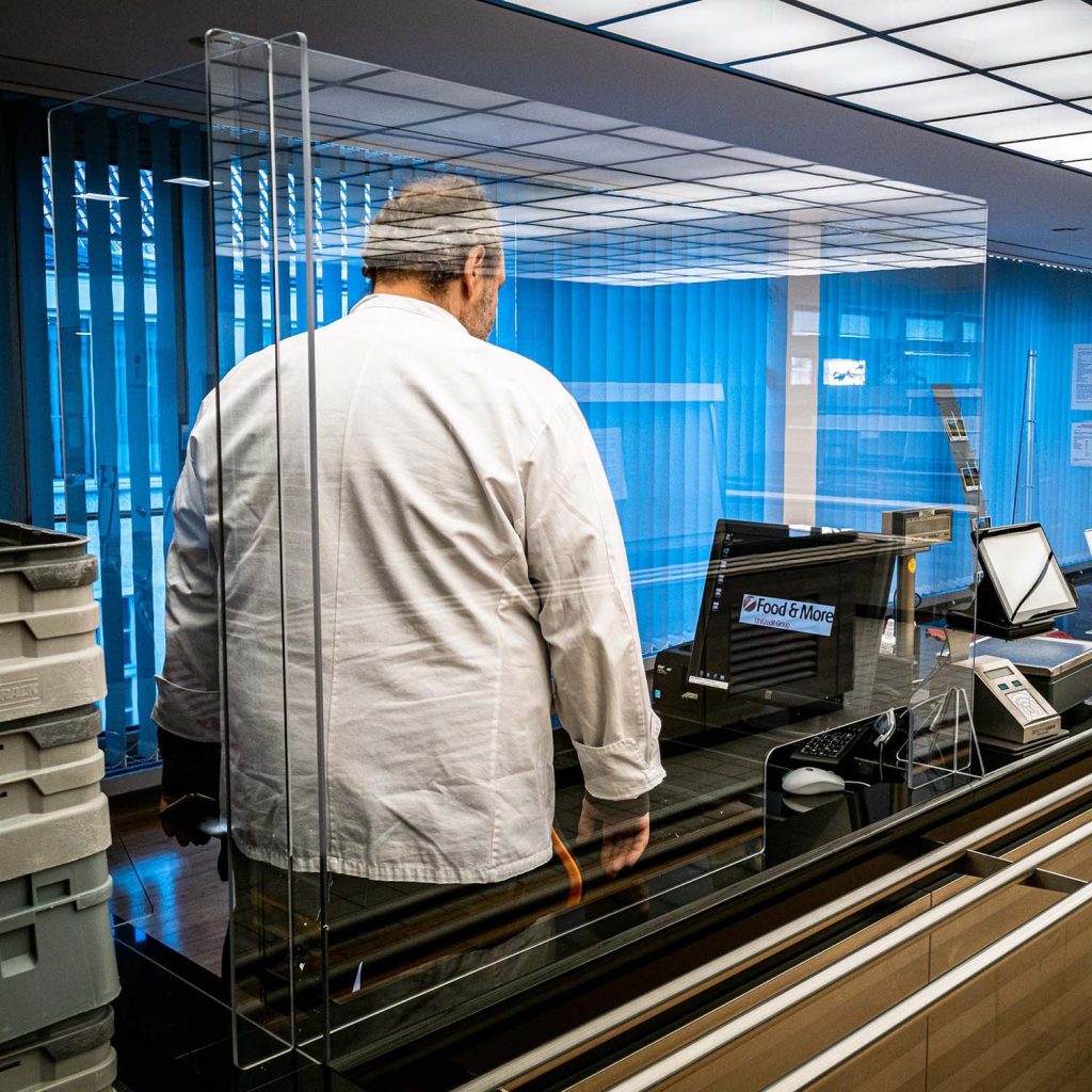 Infektionsschutzwand aus unzerbrechlichem Polycarbonat im Kassenbereich einer Kantine. Entwickelt und produziert von RIWA Display GmbH in der Universitätsstadt Garching bei München.